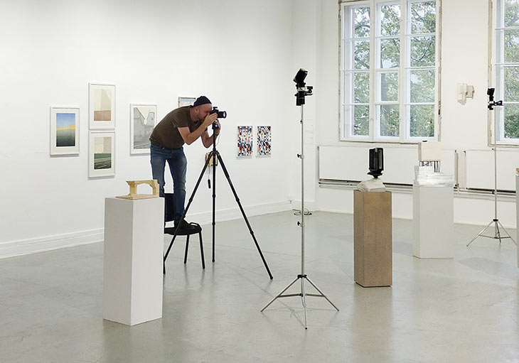 Thomas Raatz steht in Ausstellung und fotografiert Kunstwerke.